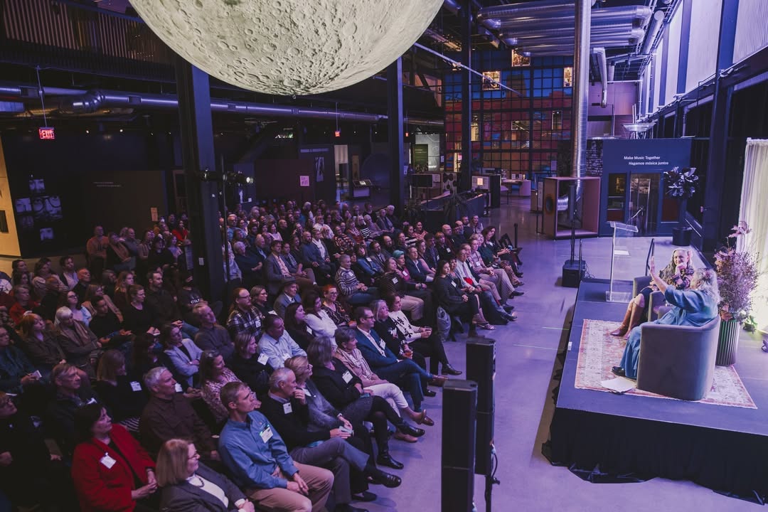 Holland Talks attendees facing a small stage inside the Luminarium, beneath a large hanging model of the moon. Holland Talks attendees facing a small stage inside the Luminarium, beneath a large hanging model of the moon. Image Credit: @bensemisch, Kiewit Luminarium Instagram.